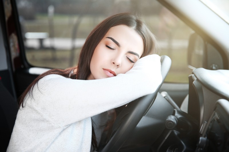 Una mujer dormida apoyada en el volante de su coche