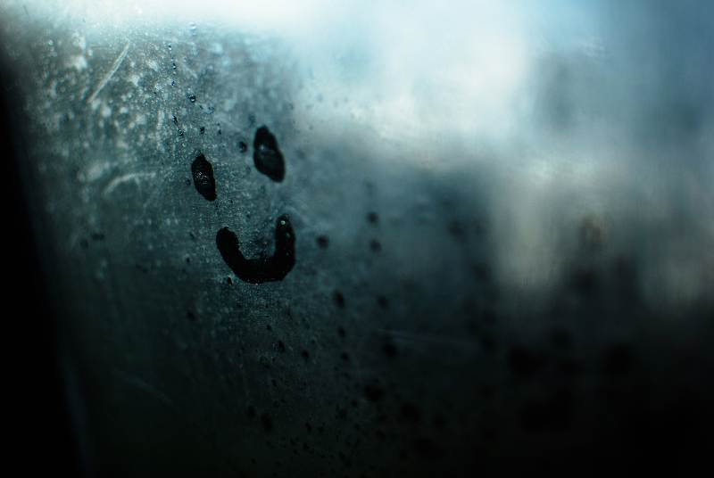 Una cara sonrinte dibujada en el vaho de un coche